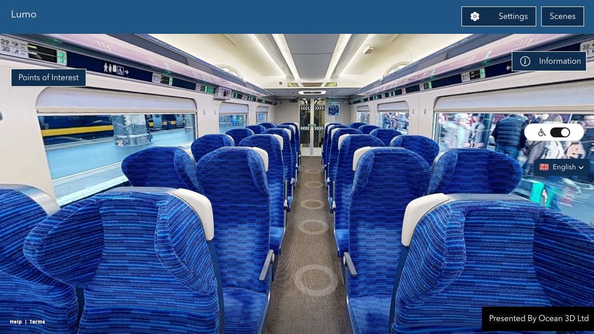 A virtual reality view from inside a Lumo train car shows blue seats arranged in rows facing each other, and a window view of people on a platform.