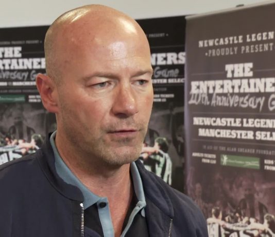 Alan Shearer in front of posters for The Entertainers 20th Anniversary Game