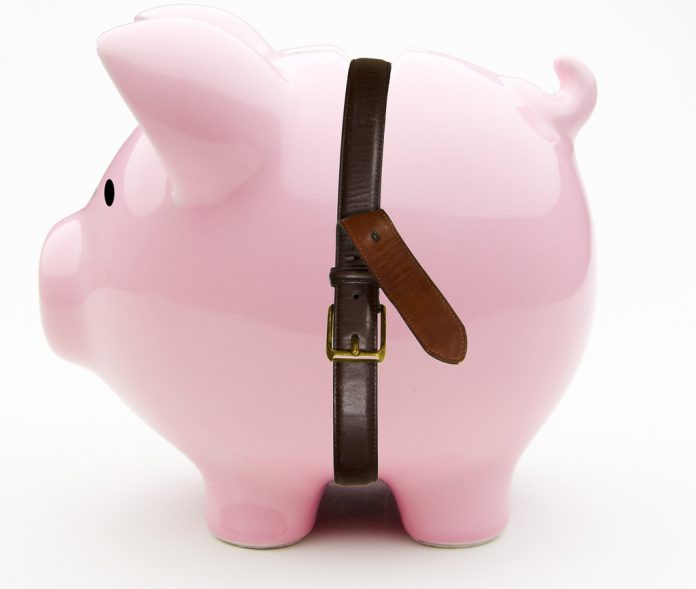 A piggy bank with a leather belt around its waist.