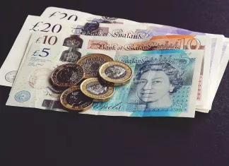 £1,200 Pay Rise Required to Keep Pace with Inflation A detailed photograph featuring a collection of British Pound notes and coins. The notes are spread out alongside various coins, illustrating the different denominations and designs of the UK's currency. This image is used to illustrate the article about the impact of inflation on salaries. Photo by Suzy Hazelwood.